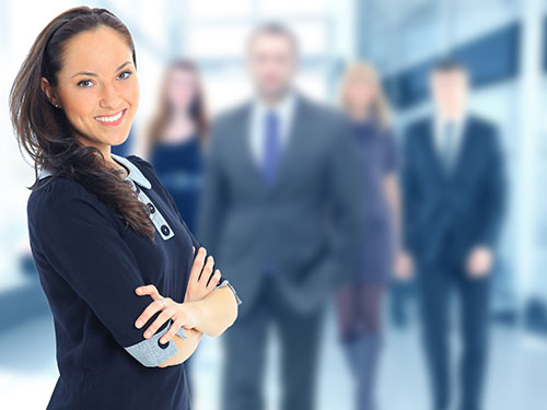 a confident female office worker smiling in front of her team members