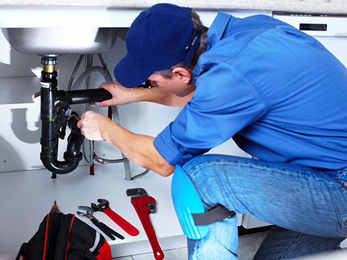 male plumber repairing a pipe under the kitchen sink